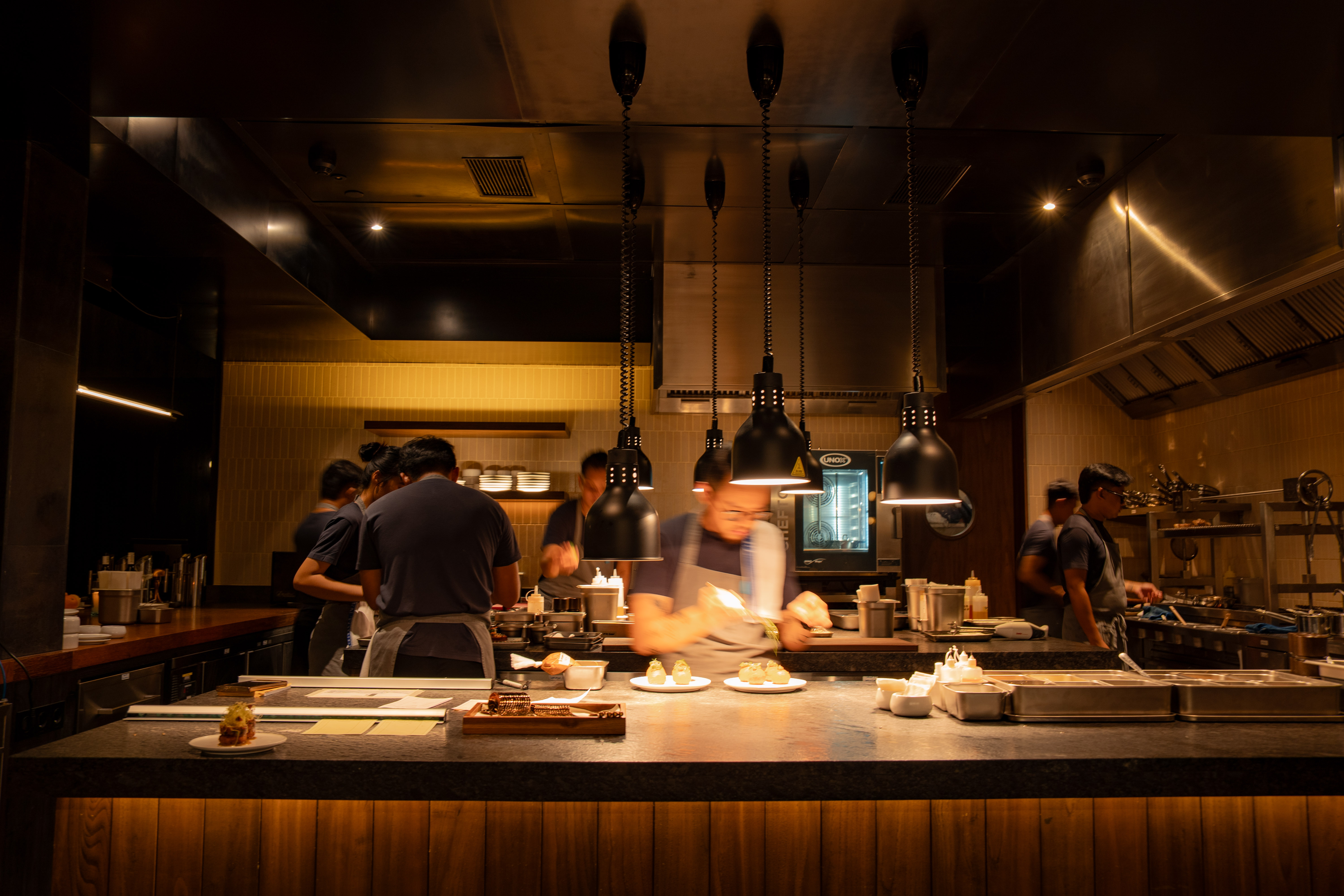 Open kitchen with culinary team preparing dishes at CURE, Regent Bali Canggu
